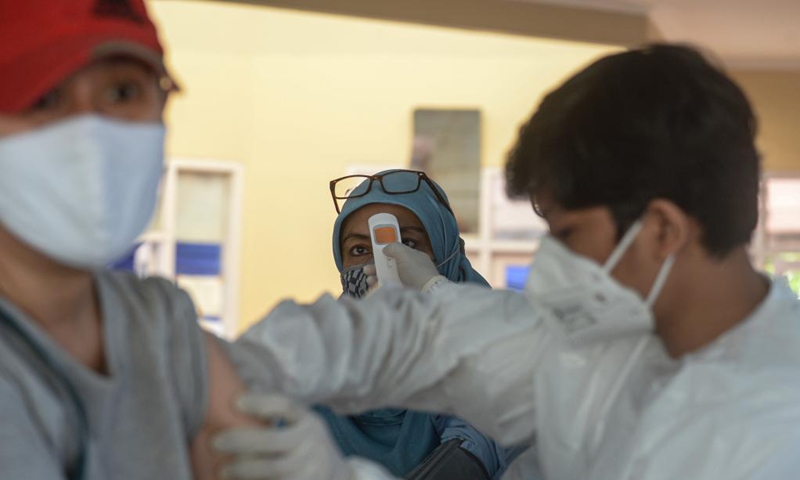 A woman takes a temperature check before receiving a dose of COVID-19 vaccine in South Tangerang, Indonesia, June 14, 2021.Photo: Xinhua