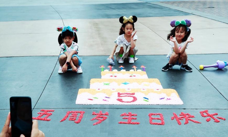 Children take photos with the birthday cake at Shanghai Disney Resort, June 16, 2021. (Photo/ Tang Yanjun)
