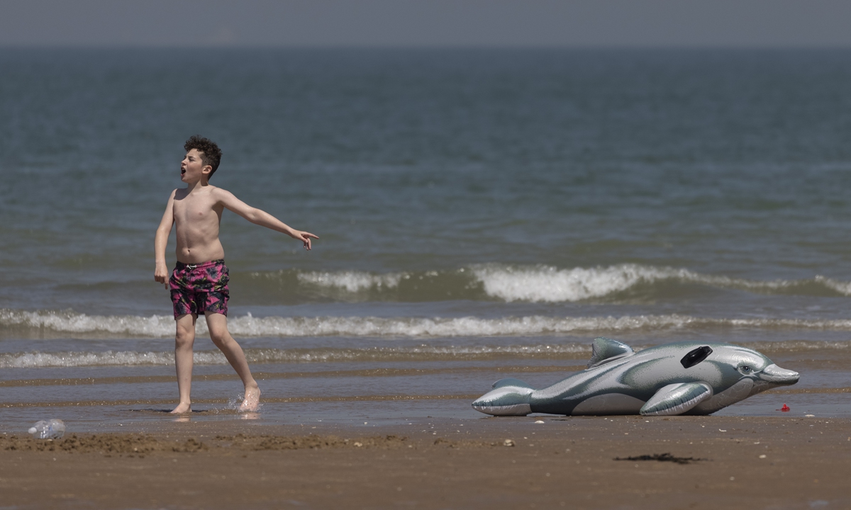 A boy gestures at an inflatable dolphin on the beach on June 2 in Margate. Photo: VCG