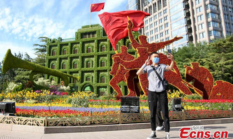 A passenger takes photos with themed flowerbeds at the Dongdan intersection along Chang'an Avenue in Beijing, June 17, 2021. Photo: China News Service