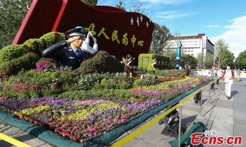 Passengers walk across a themed flowerbed at Xidan intersection in Beijing's Chang'an Avenue.  Photo: China News Service
