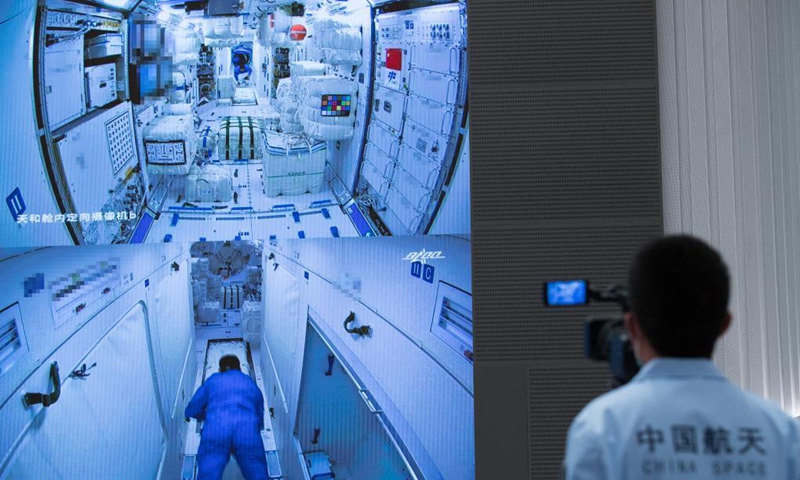 A staff member takes videos of the screen image showing three Chinese astronauts onboard the Shenzhou-12 spaceship entering the space station core module Tianhe at Beijing Aerospace Control Center in Beijing, capital of China, June 17, 2021. 