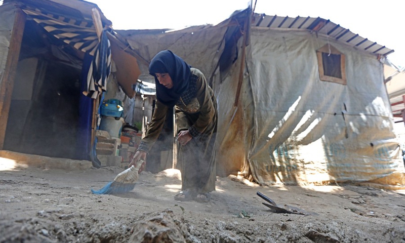 A Syrian refugee cleans in front of her tent in the Ketermaya refugee camp outside Beirut, capital of Lebanon, on June 19, 2021.(Photo: Xinhua)