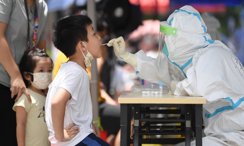 A medical worker in protective suit collects a swab sample from a boy for COVID-19 nucleic acid testing in the subdistrict of Baihedong in Liwan District of Guangzhou, south China's Guangdong Province, June 12, 2021.(Photo: Xinhua)