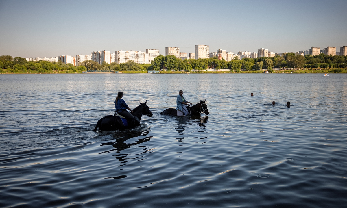 As temperatures in Moscow reach 30 C, women cool their horses off in the water at the city's Borisovskye Ponds on Sunday. Photo: AFP