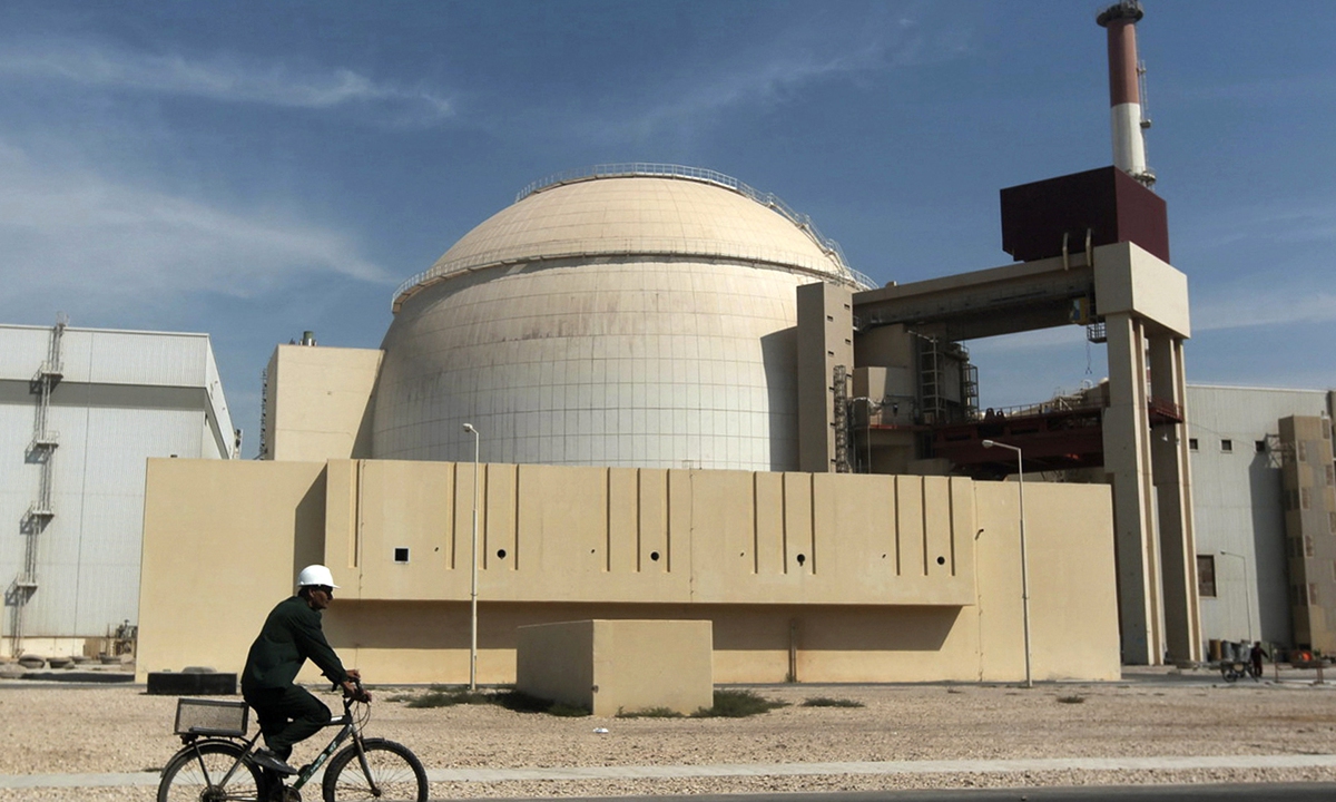 A worker rides a bicycle in front of the reactor building of the Bushehr nuclear power plant in Iran. Photo: VCG