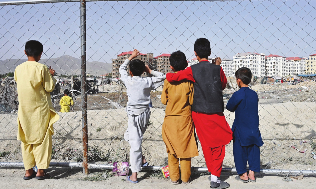 Children watch people at a camp for internally displaced people (IDP) where new apartment buildings are located in Kabul, Afghan on Monday. Photo: VCG