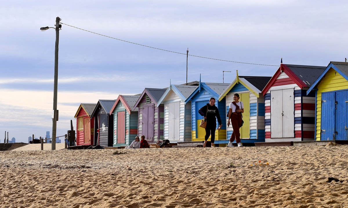People enjoy a mid-winter walk in front of the Brighton bathing boxes in Melbourne on Tuesday as the city's latest COVID-19 outbreak recedes while Sydney battles a fresh cluster, highlighting Australia's difficulty in quashing persistent small virus flare-ups. Photo: AFP