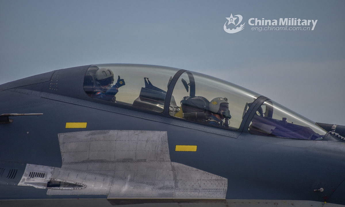 Two pilots assigned to an aviation brigade of the air force under the PLA Western Theater Command get everything ready for takeoff and give a thumbs-up during a flight training exercise on June 10, 2021. (eng.chinamil.com.cn/Photo by Cao Yukun)