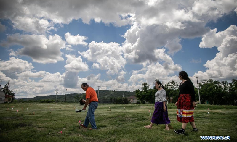 Members of the Cowessess First Nation do a ceremonial smudge at the site of unmarked graves near a former indigenous residential school in Saskatchewan, Canada, on June 27, 2021. The Cowessess First Nation, an indigenous group in Saskatchewan, on Thursday announced a preliminary discovery of 751 unmarked graves near a former indigenous residential school.(Photo: Xinhua)