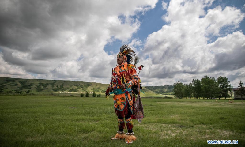 A member of the Cowessess First Nation stands in ceremonial outfit at the site of unmarked graves near a former indigenous residential school in Saskatchewan, Canada, on June 27, 2021. The Cowessess First Nation, an indigenous group in Saskatchewan, on Thursday announced a preliminary discovery of 751 unmarked graves near a former indigenous residential school.(Photo: Xinhua)