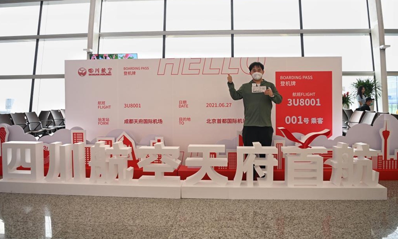 A passenger poses for a photo in front of a boarding pass model of the first flight at the Chengdu Tianfu International Airport in Chengdu, southwest China's Sichuan Province, June 27, 2021. Chengdu Tianfu International Airport in southwest China's Sichuan Province has opened for operations, with a Sichuan Airlines flight bound for Beijing taking off on Sunday morning. (Xinhua)