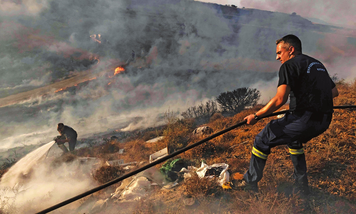 Firefighters douse the flames in an effort to contain a fire near the Kotsiatis area, on the outskirts of Cyprus' capital Nicosia on Sunday. Cyprus said a deadly forest fire that was the worst to hit the island in decades was close to being brought under control Sunday after water bombing by Greek and Israeli aircraft. Photo: VCG
