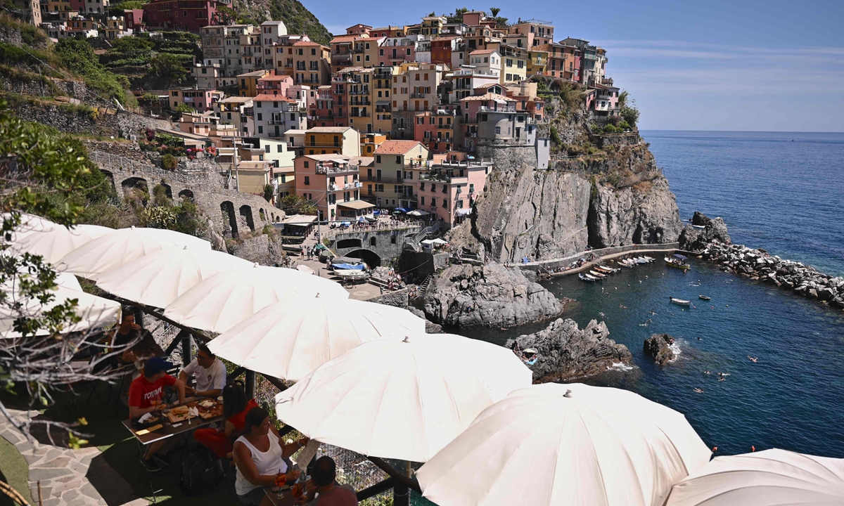 People sit at a cafe terrace overlooking the sea on June 24 in Manarola, northwest Italy. Photo: VCG