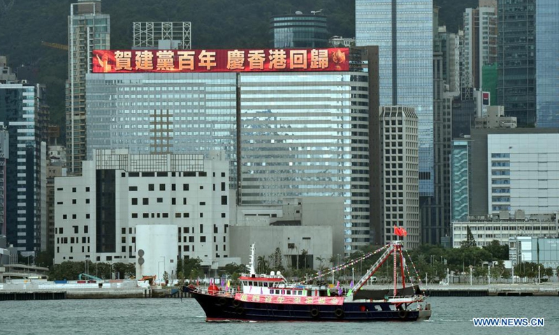 A fishing boat flying China's national flag and the flag of the Hong Kong Special Administrative Region (HKSAR) cruises at Victoria Harbour in Hong Kong, south China, July 1, 2021.Photo:Xinhua