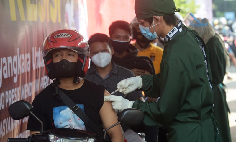 A man riding his motorbike receives a dose of COVID-19 vaccine at a drive-through vaccination site in Jakarta, Indonesia, July 2, 2021.Photo:Xinhua