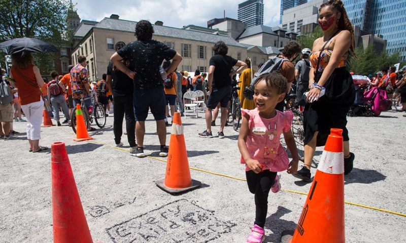 A girl runs past a Every Child Matters sign on the ground during a rally in Toronto, Canada, on July 1, 2021. Hundreds of people gathered here on Thursday to pay tribute to indigenous children whose bodies were found in mass graves near former indigenous residential schools in Canada. Photo:Xinhua