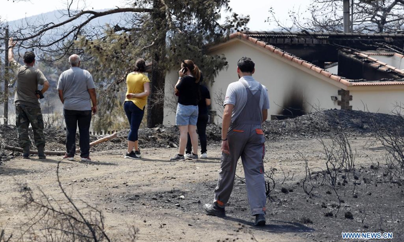 People are seen near a burned house at Ora village in Larnaca district, Cyprus, July 4, 2021. Four people were killed in a mammoth forest fire which has been raging for almost 24 hours in a mountainous area of Cyprus, police said on Sunday. (Photo: Xinhua)