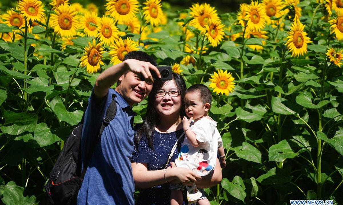 People pose for photos with sunflowers at the Beijing Olympic Forest Park in Beijing, capital of China, July 4, 2021. (Xinhua/Chen Yehua)