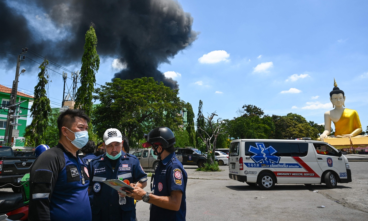 Rescue workers gather, as smoke billows from an explosion and fire at a plastics factory, in Bangkok, Thailand on Monday. Photo: VCG