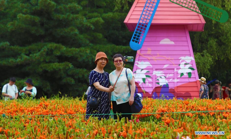 People take selfies beside lilies at Shenshuiwan Park in Shenyang, northeast China's Liaoning Province, July 6, 2021. (Xinhua/Yang Qing)

