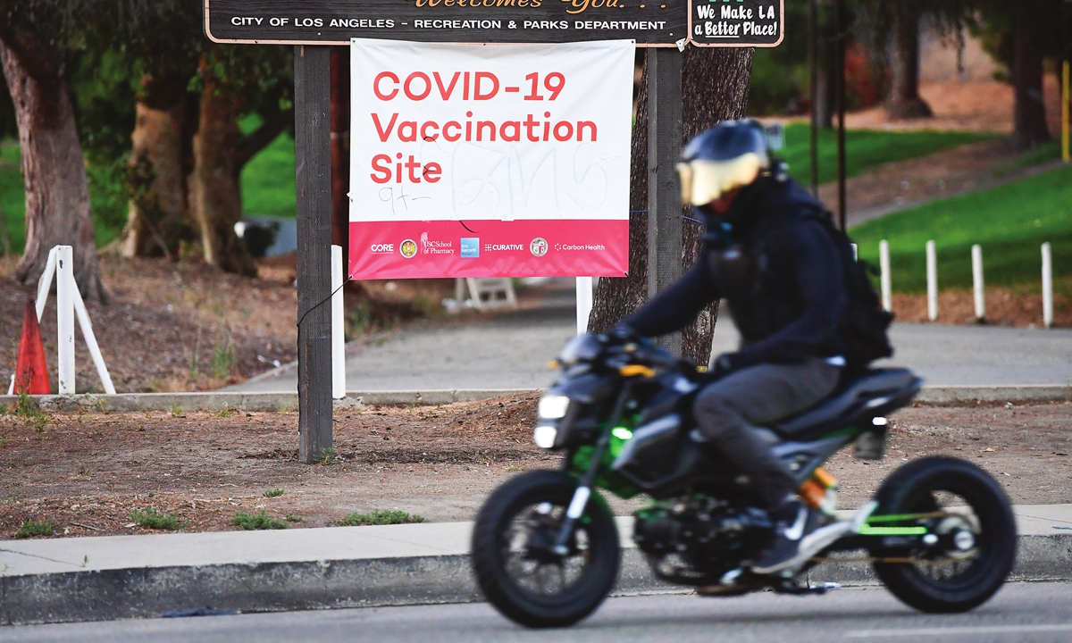 A motorcyclist rides past a COVID-19 vaccine site in Los Angeles, California on Tuesday. A rapid rise in the 