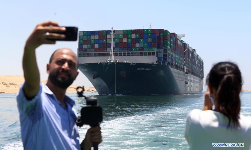People take photos of the Ever Given container ship sailing on the Suez Canal in Ismailia Province, Egypt, July 7, 2021. The Ever Given container ship which blocked the Suez Canal for nearly a week in March began its journey out of the canal on Wednesday, said Suez Canal Authority (SCA) Chairman Osama Rabie.(Photo: Xinhua)