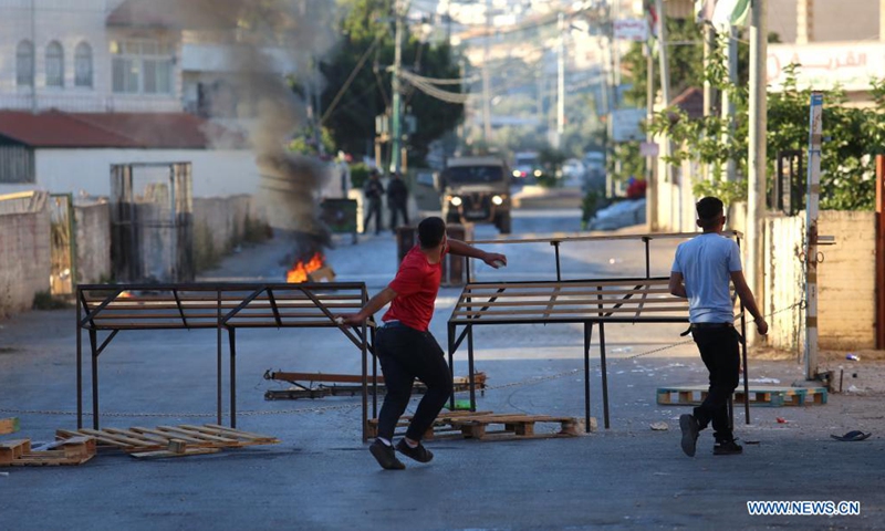 Protesters hurl stones at members of Israeli border police during clashes after Israeli forces blew up the house of Palestinian-American Muntasser Shalaby, in the village of Turmus Ayya near the West Bank city of Ramallah, July 8, 2021. The Israeli army said on Thursday that its forces demolished the family home of a Palestinian-American accused of carrying out a deadly gun attack in the Israel-occupied West Bank in May.Photo:Xinhua