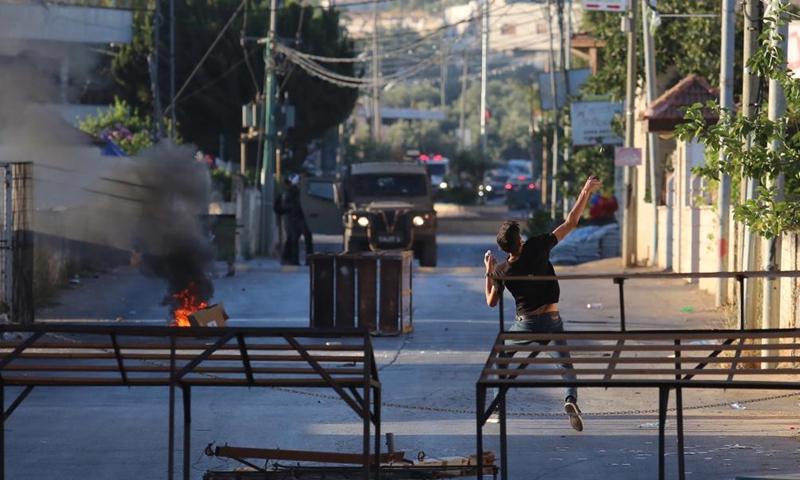 A protester hurls stones at members of Israeli border police during clashes after Israeli forces blew up the house of Palestinian-American Muntasser Shalaby, in the village of Turmus Ayya near the West Bank city of Ramallah, July 8, 2021. The Israeli army said on Thursday that its forces demolished the family home of a Palestinian-American accused of carrying out a deadly gun attack in the Israel-occupied West Bank in May.Photo:Xinhua