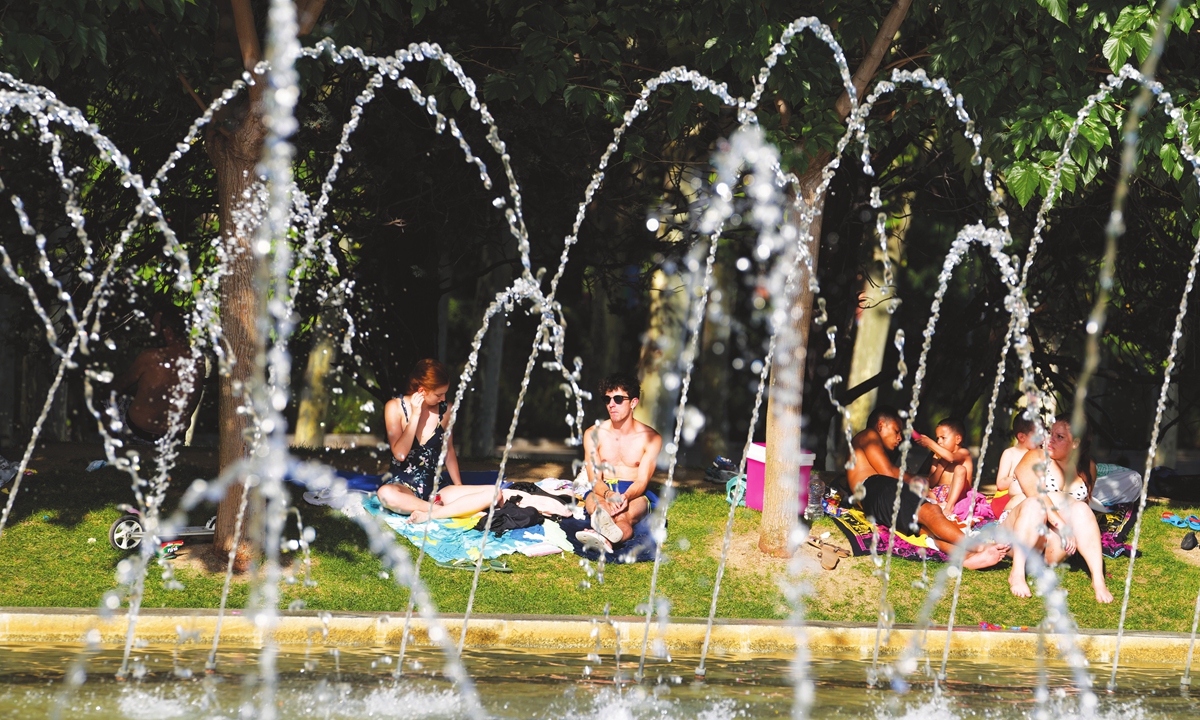 People sit by a fountain in a park in Madrid, Spain on Saturday. Residents in Spain are trying to stay as cool as possible as forecasts showed weekend temperatures could rise above 40 C in large parts of the Iberian Peninsula. The heat is expected to scorch central south Spain on Saturday before spreading east over the next two days.  Photo: VCG