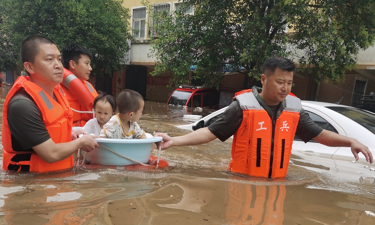 People's Liberation Army soldiers transfer to children to safe places in floods-ravaged Weihui of Xinxiang, Central China's Henan on Thursday. Photo: cnsphoto 