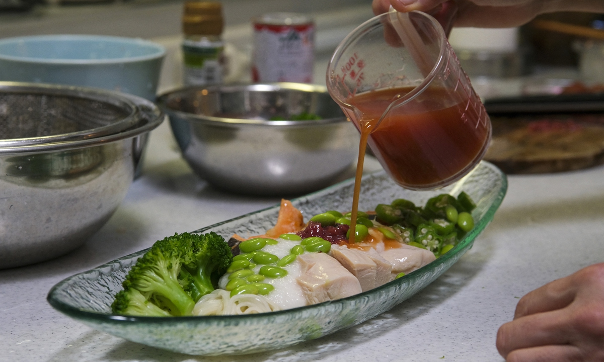 A Japanese housewife, one of the winners in the 2020 Tokyo Olympic village food recipe contest, pours sauce on her dish at a kitchen in Tokyo, Japan on Monday. Photo: AFP