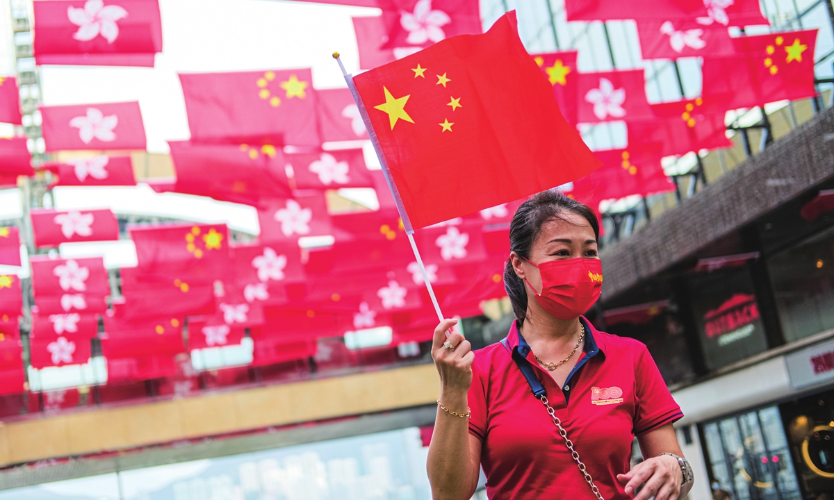 A woman holds a Chinese national flag and stands under the flags of China and Hong Kong SAR on July 1 to celebrate the 100th anniversary of the founding of the Chinese Communist Party and the 24th anniversary of Hong Kong return to China. Photo: IC