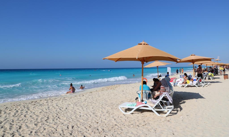 People enjoy themselves on the beach in El Alamein, Matrouh province, north coast of Egypt, on July 17, 2021. El Alamein is a town on the coast of the Mediterranean Sea in Egypt. It boasts silvery sandy beach and sapphire-color seawater, usually visited by many tourists every year.(Photo: Xinhua)