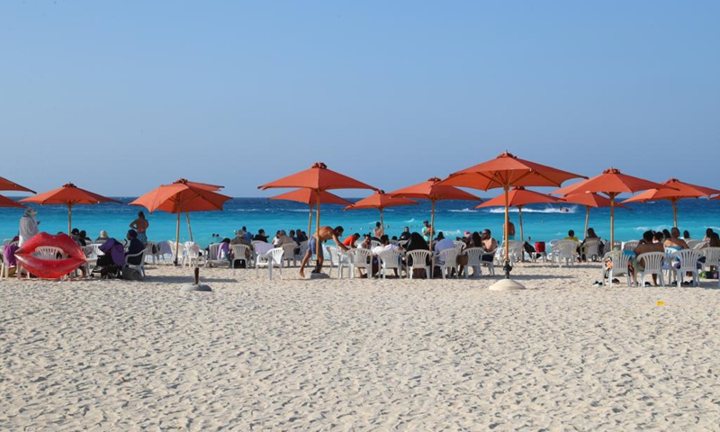 People enjoy themselves on the beach in El Alamein, Matrouh province, north coast of Egypt, on July 17, 2021. El Alamein is a town on the coast of the Mediterranean Sea in Egypt. It boasts silvery sandy beach and sapphire-color seawater, usually visited by many tourists every year.(Photo: Xinhua)
