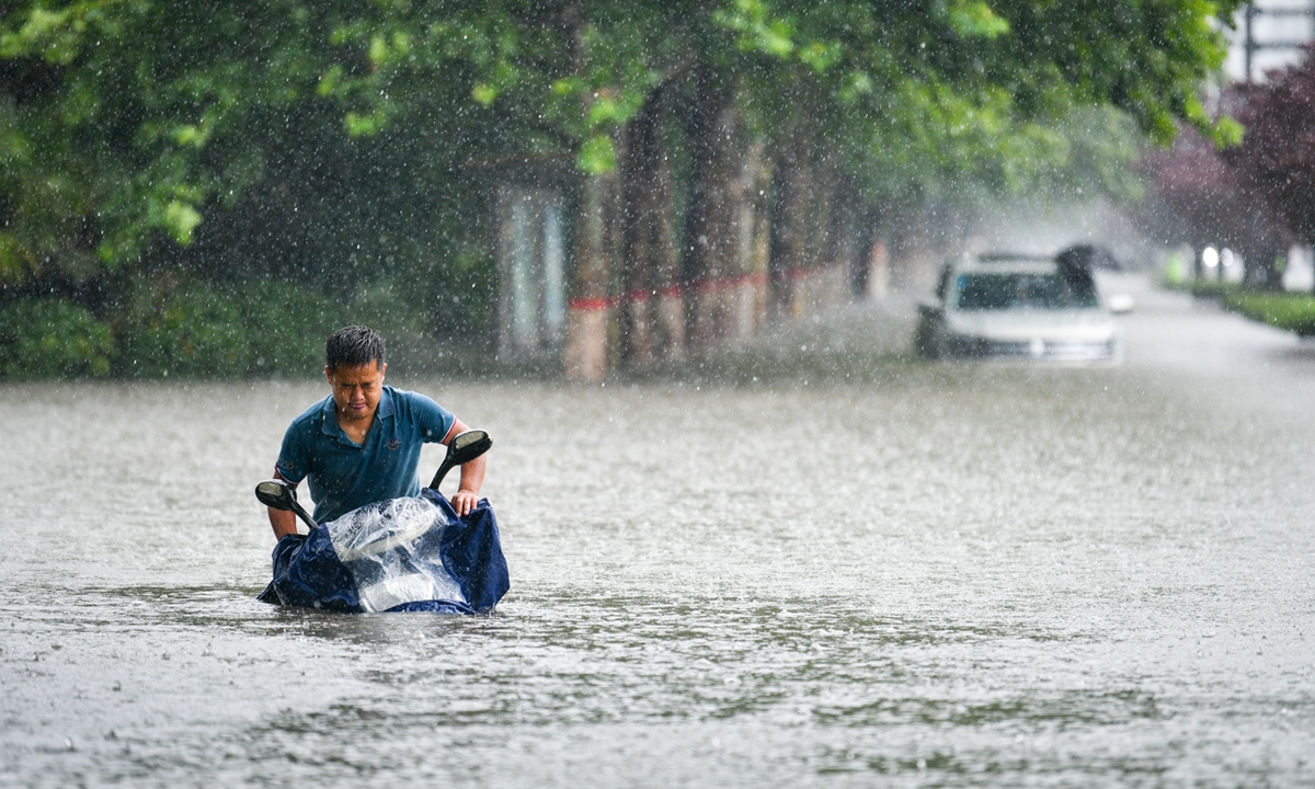 A man on Tuesday drives a motorbike through waist-high water after a night of rainstorms in Zhengzhou, capital of Central China's Henan Province. Photo: IC