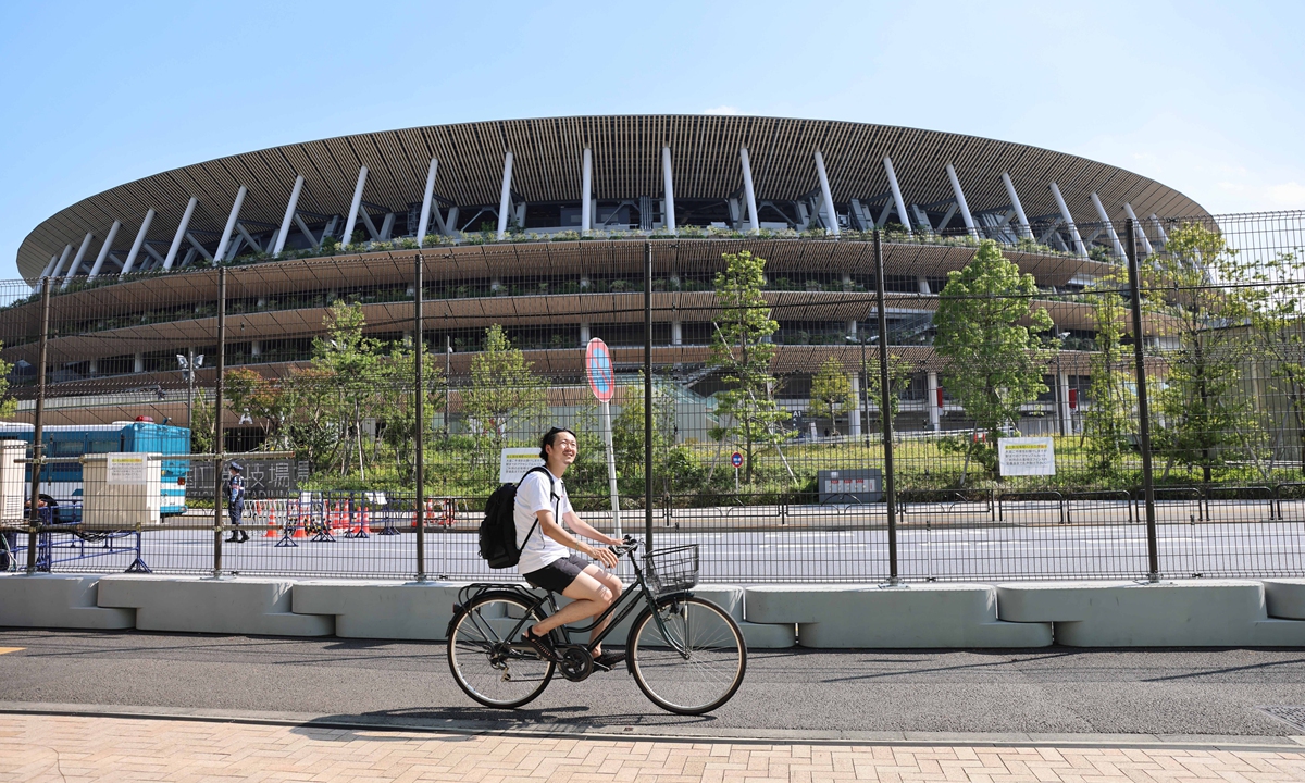 A man rides a bike past a security fence surrounding the National Stadium in Tokyo, Japan on Monday. Photo: VCG