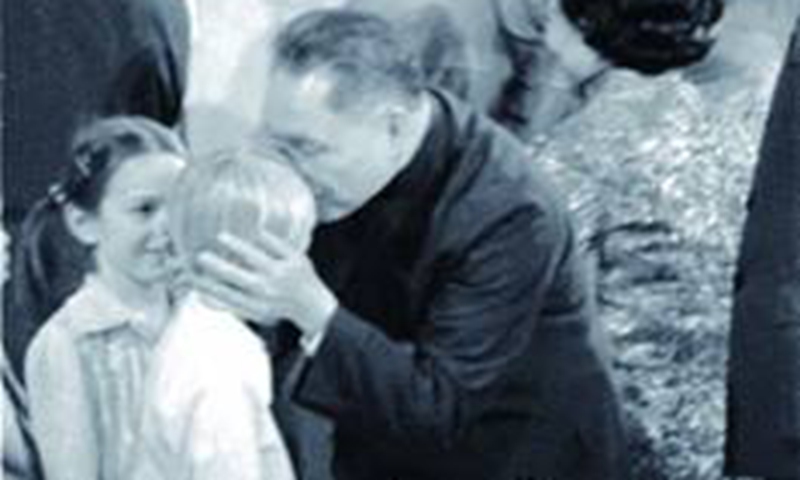 Deng Xiaoping waves at the audience and kisses the forehead of a kid at the John F. Kennedy Center for the Performing Arts.