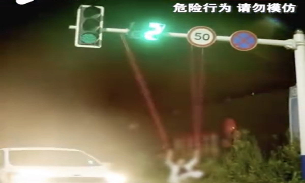 In a video clip circulating on the internet on Monday, the man is seen swinging on a swing hanging from the traffic light bracket on a street as cars passed by. Photo: Sina Weibo
