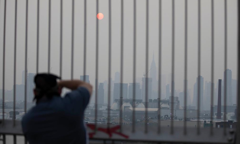 A man takes photo of Manhattan skyline in a thick haze in New York, the United State, July 20, 2021. Smoke from the wildfires in the western U.S. has contributed to the haze, according to local weather service.(Xinhua)