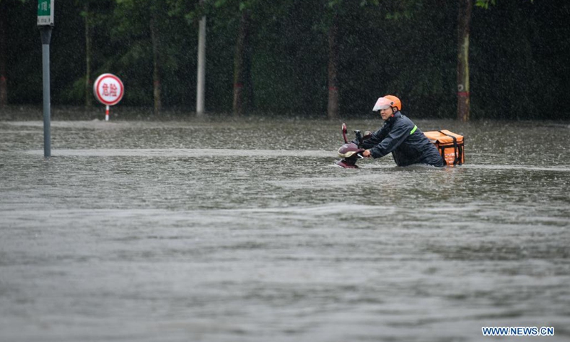 A courier wades through a waterlogged road in Zhengzhou, capital of central China's Henan Province, July 20, 2021. More than 144,660 residents have been affected by torrential rains in central China's Henan Province since July 16, and 10,152 have been relocated to safe places, the provincial flood control and drought relief headquarters said Tuesday.(Photo: Xinhua)