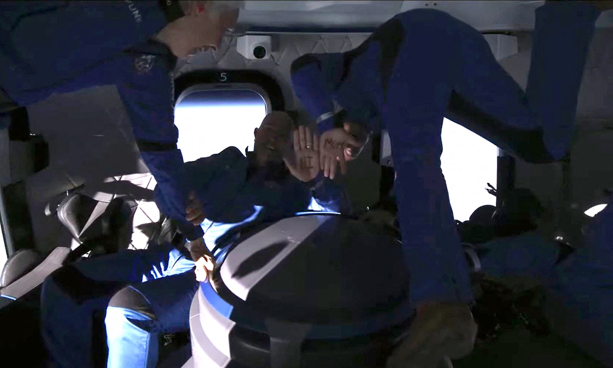 Jeff Bezos (right) and his brother Mark Bezos (middle) spell out Hi Mom on their hands during the space flight.  Photo: AFP