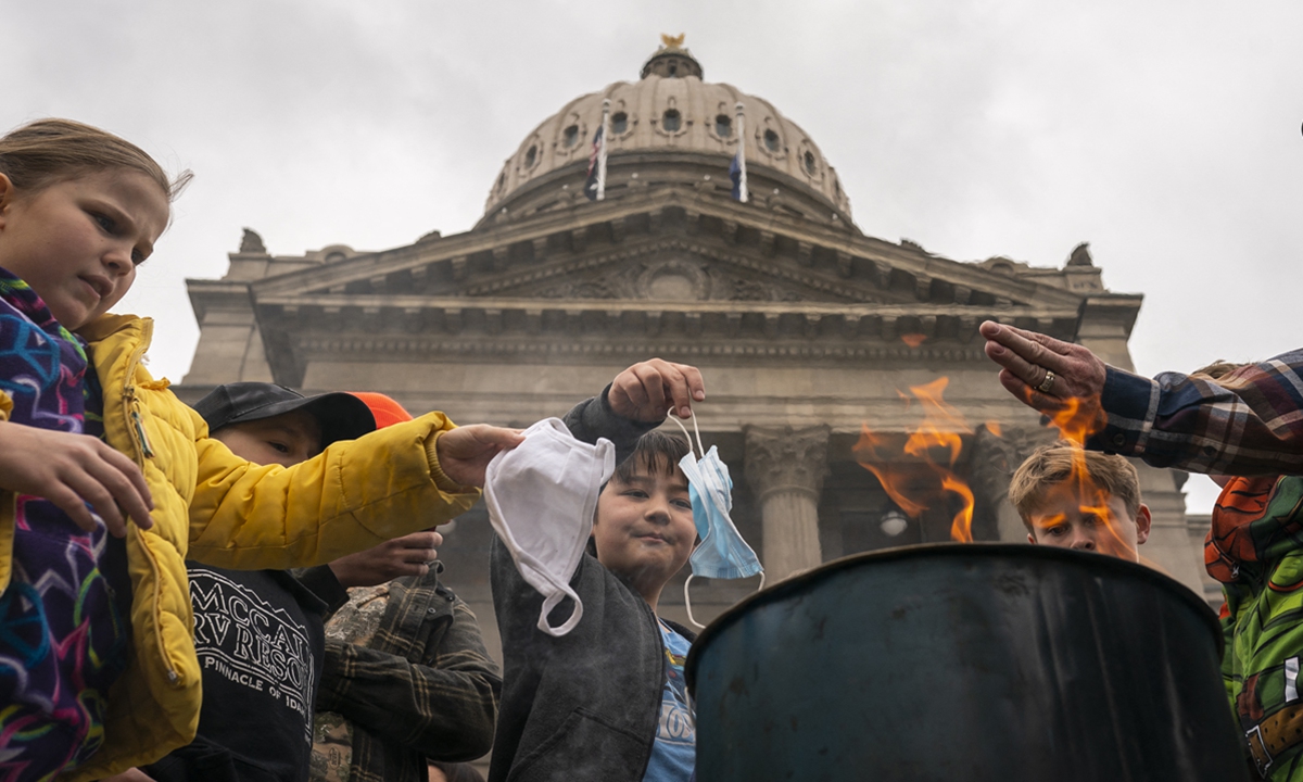Young attendees toss surgical masks into a fire during a mask-burning rally at the local statehouse on March 6 in the US state of Idaho. Citizens and politicians gathered in at least 20 cities across the state to protest COVID-19 restrictions. Photo: AFP