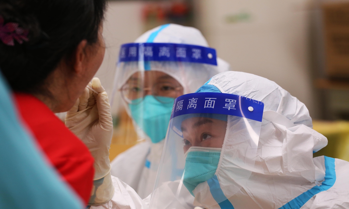 Medical workers take swab sample from a woman for a COVID-19 test in Nanjing, East China's Jiangsu Province on Sunday. Nanjing, which has a population of more than 9.3 million, carried out a second round of citywide nucleic acid testing starting on Sunday. Photo: VCG
