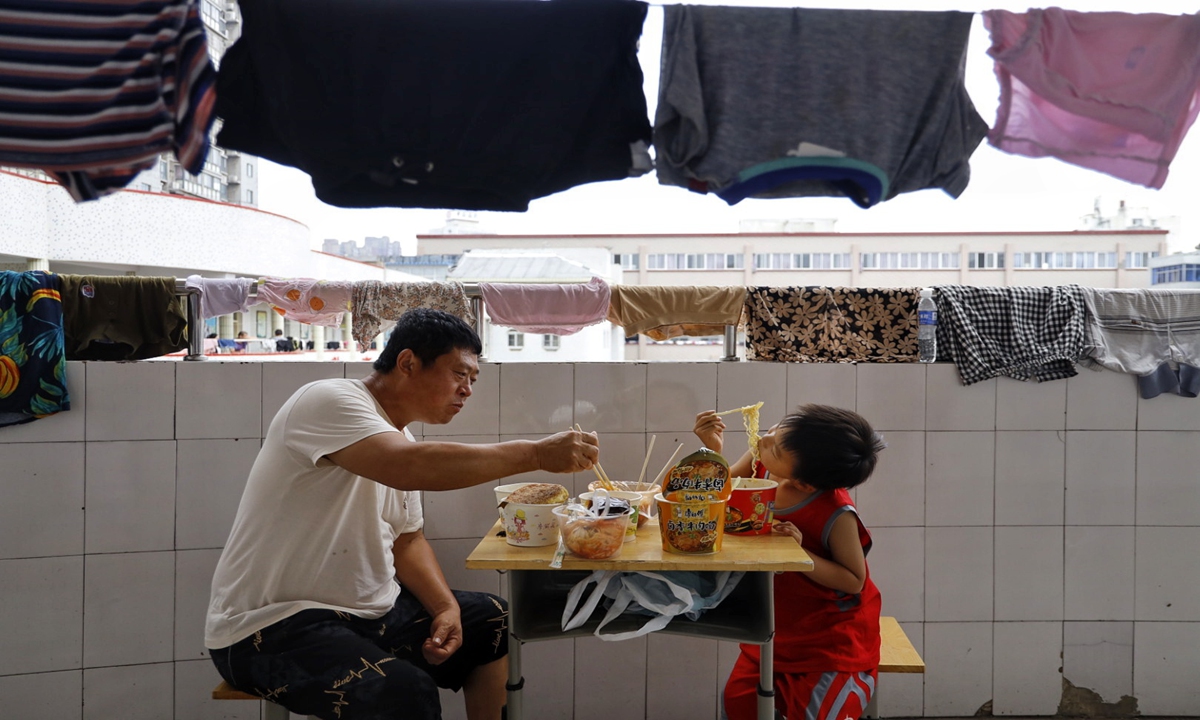 A father and his son have lunch in a classroom building on Sunday after being displaced by flooding and relocated at a primary school in Xinxiang, Central China's Henan Province on Sunday. The school was turned into a shelter to house 1,000 residents evacuated from flooded villages. Photo: Li Hao/GT