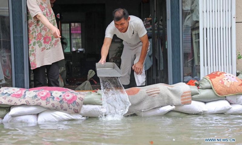 A man tries to clear water out of his house in Zhoushan, east China's Zhejiang Province, July 25, 2021. China's national observatory on Sunday continued its orange alert for Typhoon In-Fa, which made landfall in Zhejiang at around Sunday noon. (Photo: Xinhua)