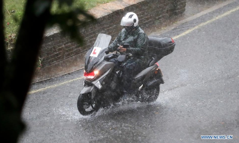 A motorcyclist rides on a flooded road during a heavy rain in London, Britain, on July 25, 2021. Heavy downpours and thunderstorms have caused severe flash flooding in parts of London on Sunday, according to local media.(Photo: Xinhua)