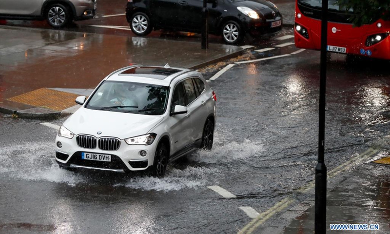 A car runs on a flooded road during a heavy rain in London, Britain, on July 25, 2021. Heavy downpours and thunderstorms have caused severe flash flooding in parts of London on Sunday, according to local media.(Photo: Xinhua)