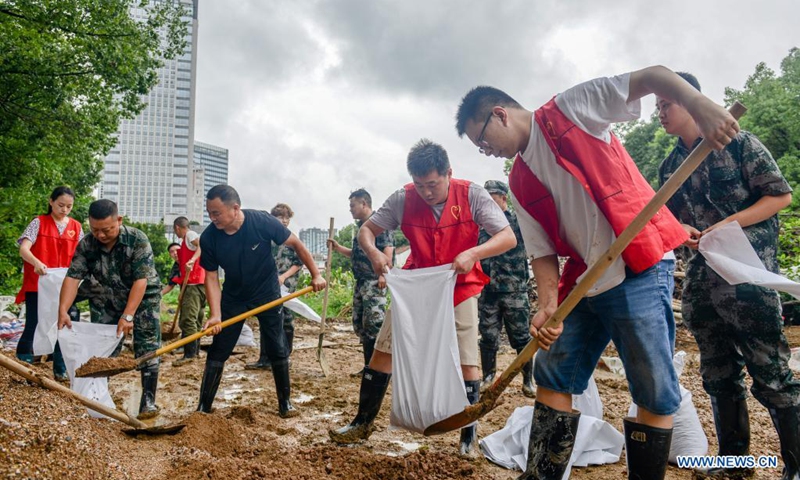 People fill up sandbags to reinforce river banks in Changxing County of Huzhou City, east China's Zhejiang Province, July 25, 2021. China's national observatory on Sunday continued its orange alert for Typhoon In-Fa, which made landfall in Zhejiang at around Sunday noon.(Photo: Xinhua)