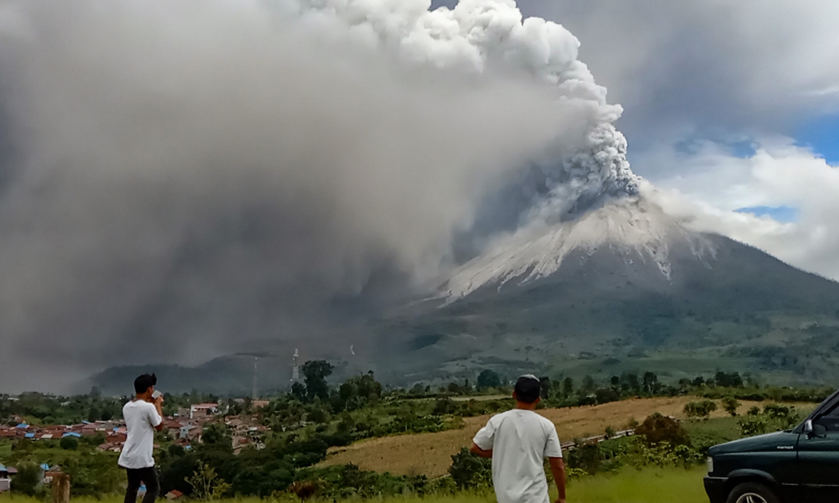 People watch a massive column of smoke and ash from Mount Sinabung from Karo, North Sumatra, Indonesia on Wednesday. The eruption  lasted about 12 minutes, per local agency. Photo: AFP